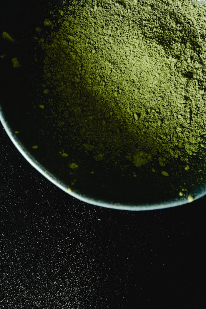 Intriguing close-up of matcha powder in a bowl against a dark background, highlighting texture.